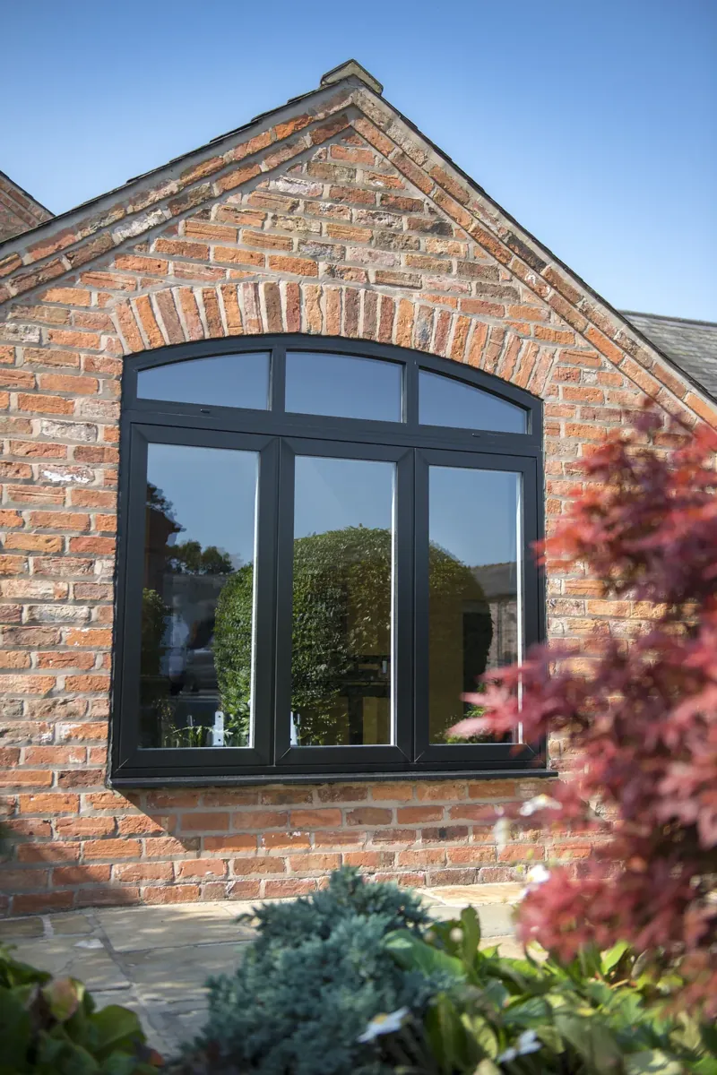 An arched-head aluminium window in a brick gable