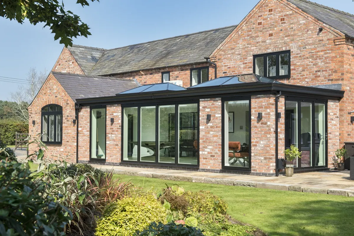 A continuous run of dark aluminium glazing on a brick barn