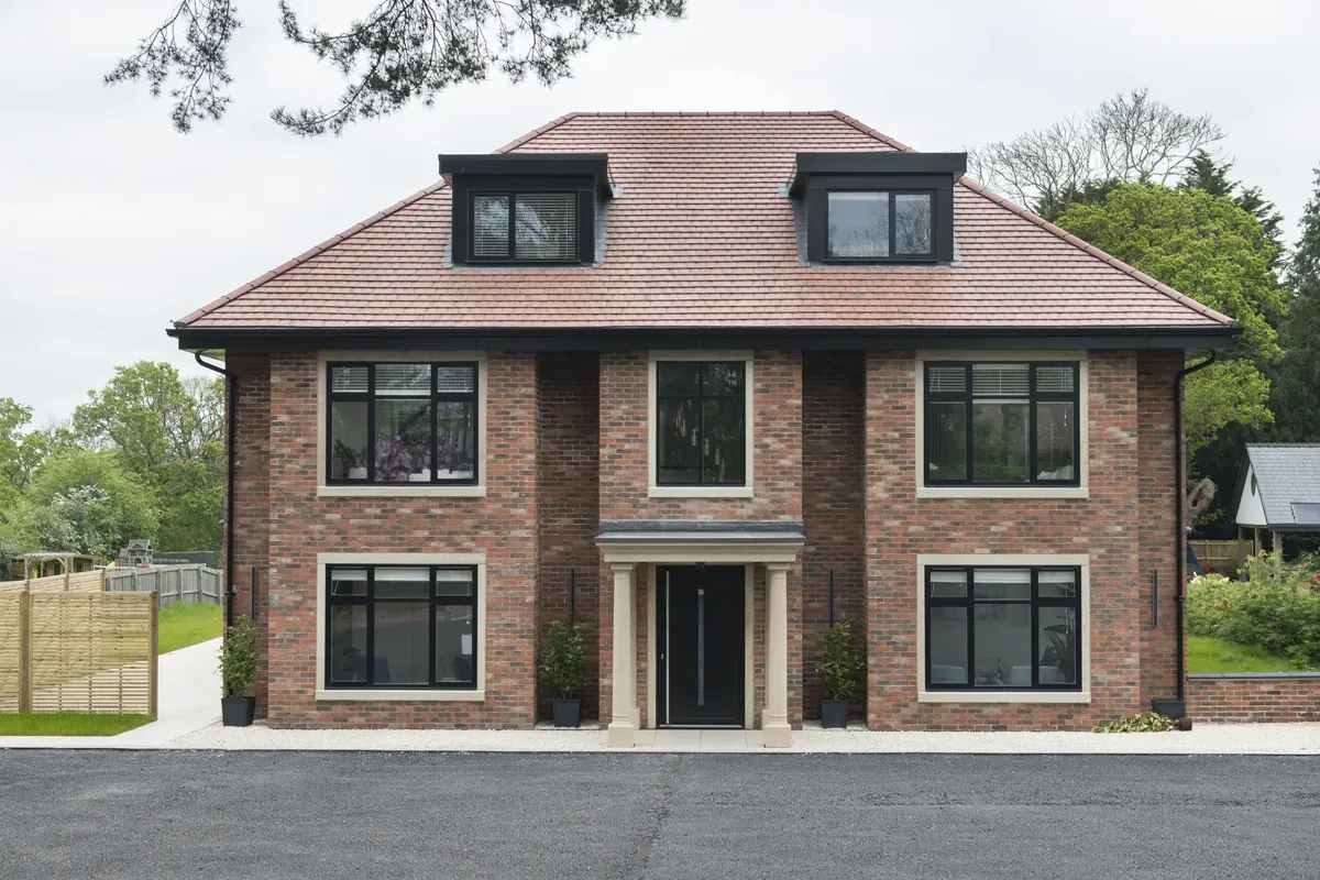 Black aluminium windows across the front of a brick house