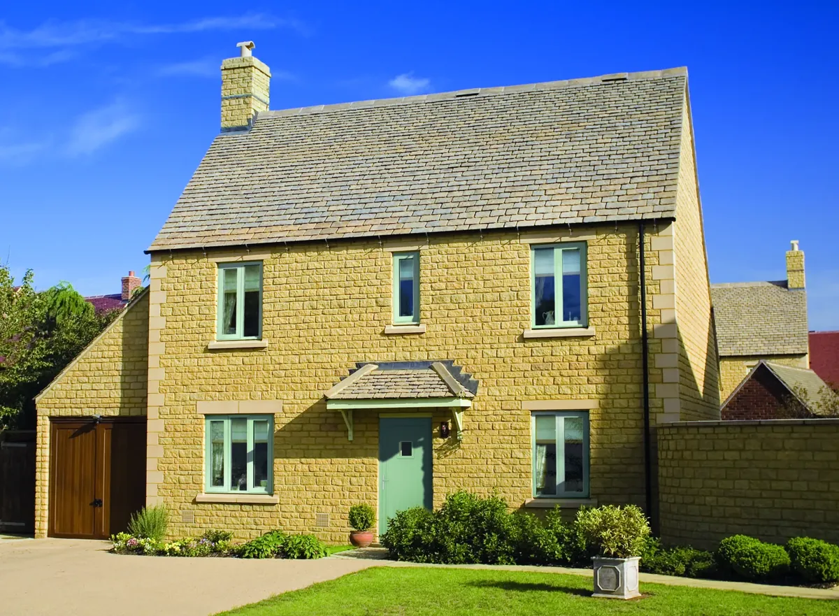 Sage-green aluminium casement windows in a stone-built house