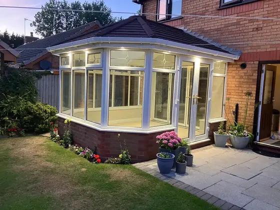 The finished conservatory with its new tiled roof, lit at dusk