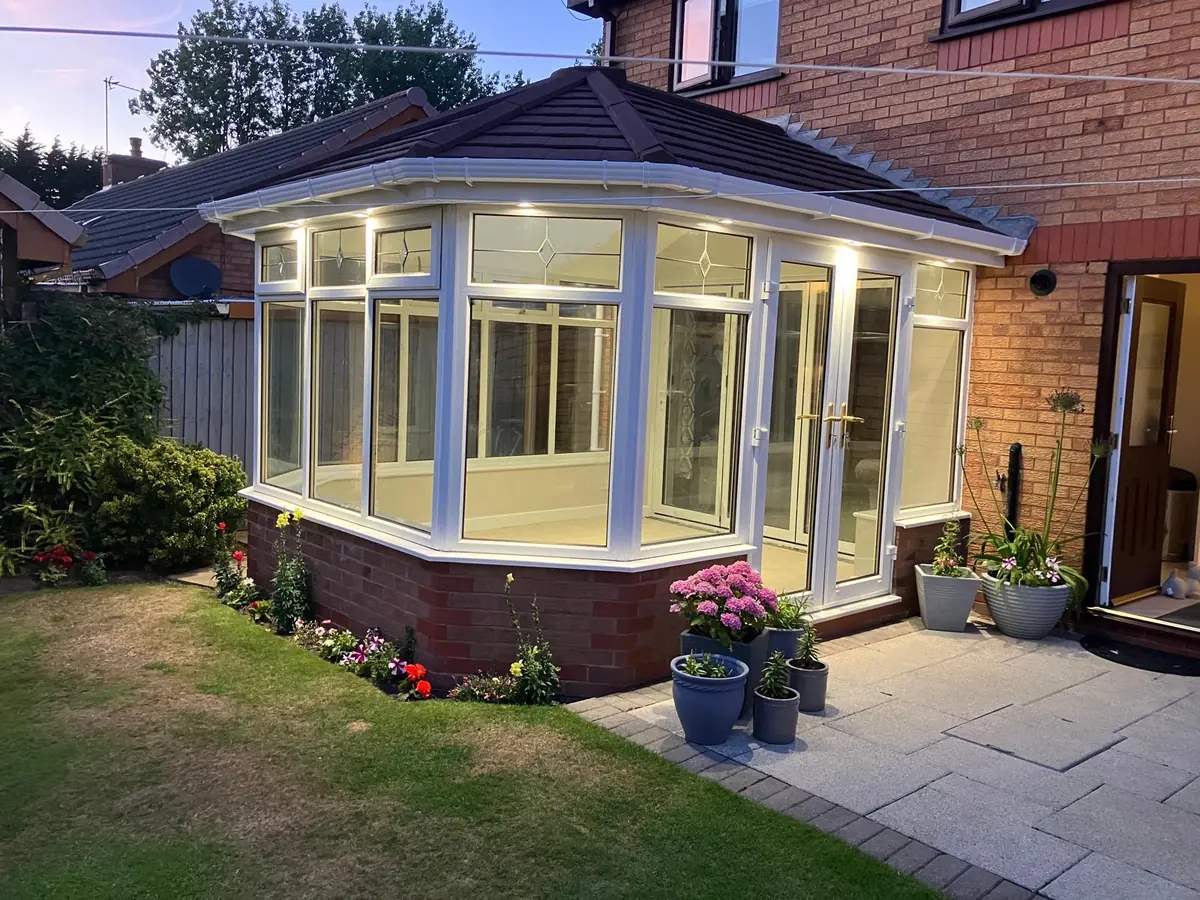 The finished conservatory with its new tiled roof, lit at dusk