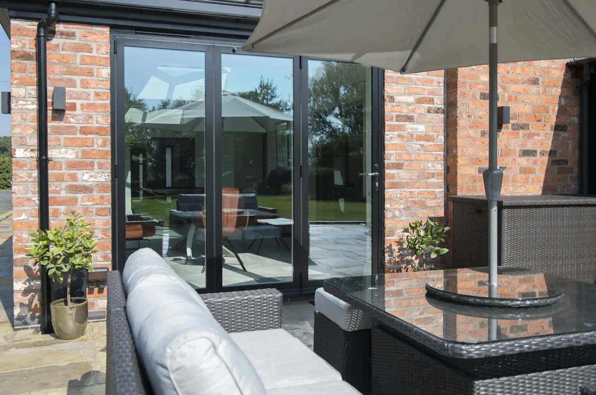 Sliding doors onto a paved terrace with garden furniture