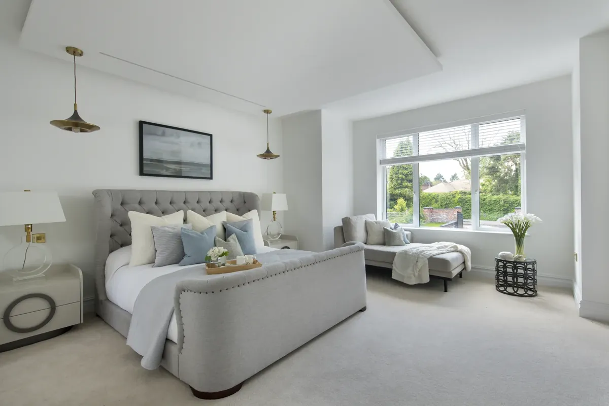 A bedroom with a wide window looking over the garden