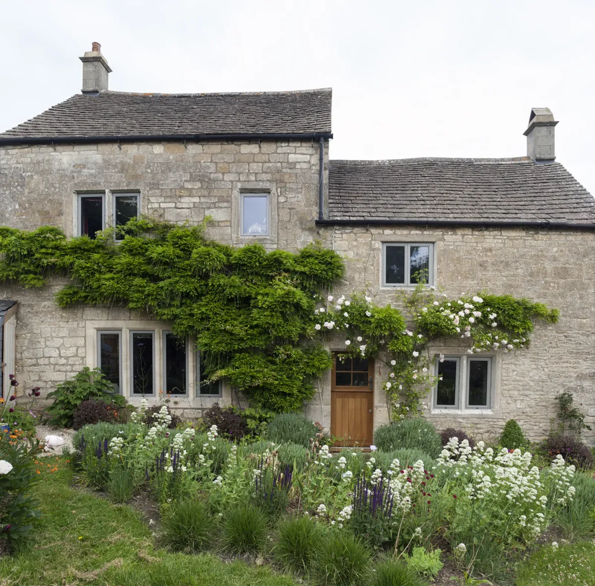 A stone cottage with a dormer window and climbing plants