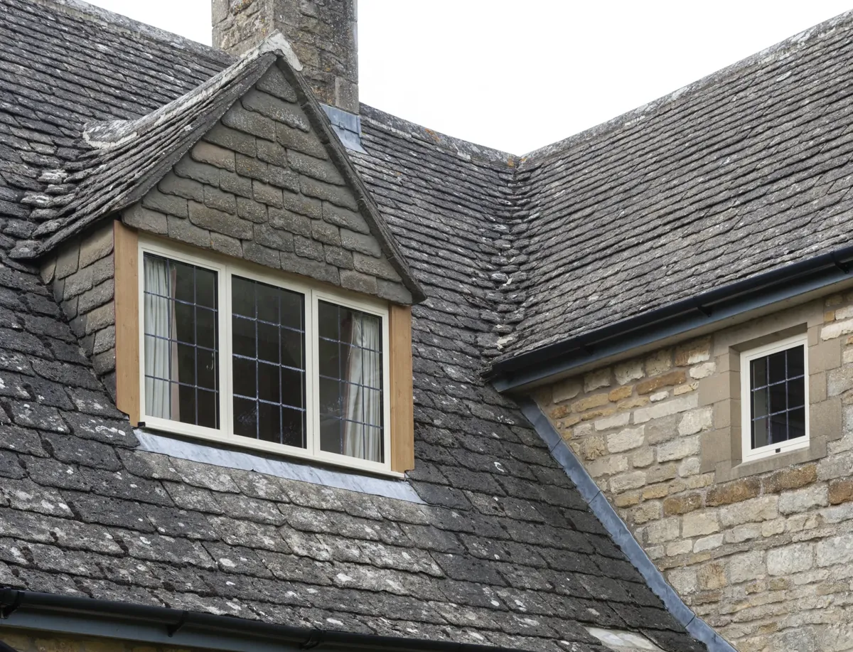 Steel-look windows in a stone dormer with a slate roof