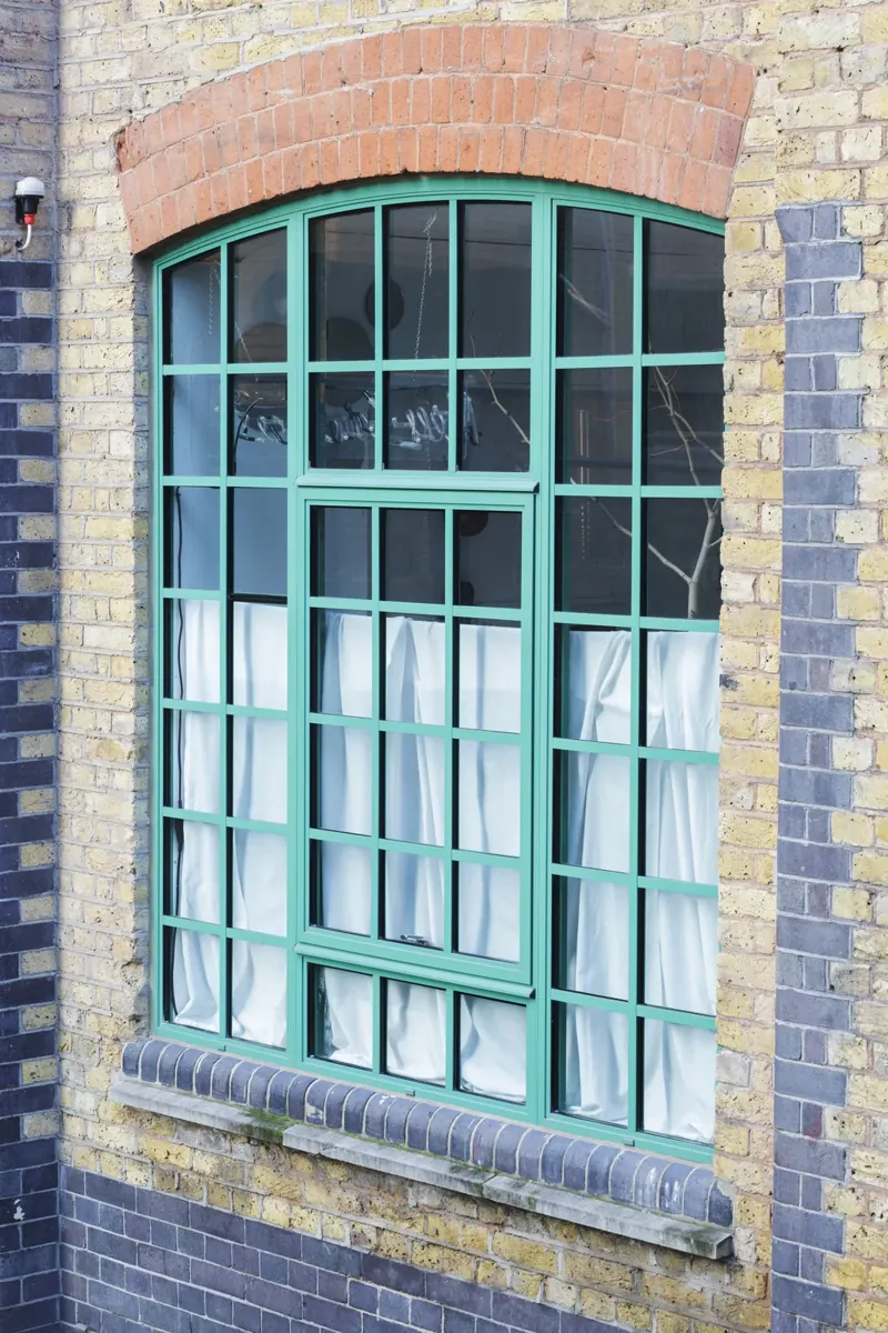 Green-framed steel-look windows in a brick elevation