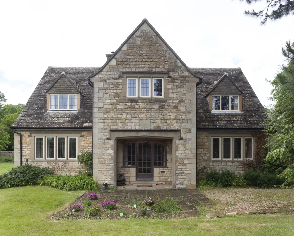 The front elevation of a stone house with steel-look windows