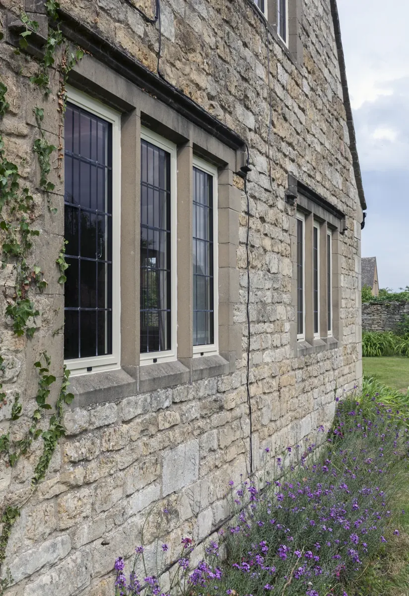 A run of leaded steel-look windows along a stone elevation
